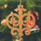 Intricate Victorian-style fretwork Christmas tree ornament handcrafted from natural hardwood with visible wood grain, showcasing symmetrical curls, loops, and ornate cut-out designs.