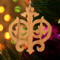 Intricate Victorian-style fretwork Christmas tree ornament handcrafted from natural hardwood with visible wood grain, showcasing symmetrical curls, loops, and ornate cut-out designs.