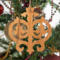 Intricate Victorian-style fretwork Christmas tree ornament handcrafted from natural hardwood with visible wood grain, showcasing symmetrical curls, loops, and ornate cut-out designs.