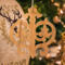 Intricate Victorian-style fretwork Christmas tree ornament handcrafted from natural hardwood with visible wood grain, showcasing symmetrical curls, loops, and ornate cut-out designs.