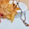 25 inch long handmade necklace with golden quartz leaf pendant, mahogany obsidian beads, and copper chain displayed with fall leaves