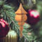 Handcrafted miniature wooden birdhouse ornament shaped like an icecicle with a pointed roof and base, featuring a rounded entrance hole and a perched bird, and made from reclaimed hardwoods finished with a satin shellac.