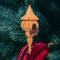 Handcrafted miniature wooden birdhouse ornament shaped like an icecicle with a pointed roof and base, featuring a rounded entrance hole and a perched bird, and made from reclaimed hardwoods finished with a satin shellac.