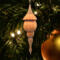 Handcrafted miniature wooden birdhouse ornament shaped like an icecicle with a pointed roof and base, featuring a rounded entrance hole and a perched bird, and made from reclaimed hardwoods finished with a satin shellac.