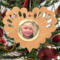 Wooden heart-shaped ornament with scalloped edges and an oak grain finish, featuring a removable round gold frame that holds a photo of a smiling blonde child.