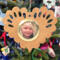 Wooden heart-shaped ornament with scalloped edges and an oak grain finish, featuring a removable round gold frame that holds a photo of a smiling blonde child.