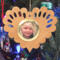 Wooden heart-shaped ornament with scalloped edges and an oak grain finish, featuring a removable round gold frame that holds a photo of a smiling blonde child.