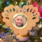 Wooden heart-shaped ornament with scalloped edges and an oak grain finish, featuring a removable round gold frame that holds a photo of a smiling blonde child.