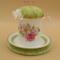This is a frontal view showing the pincushion bobbin holder sitting on the trivet. The trim on the saucer is complemented by the fabric.