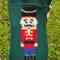A close up of the Nutcracker pocket. He's wearing a red coat, blue pants, and black boots and hat, with yellow detailing.