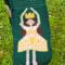 A close up of the ballerina pocket. She's wearing a pink dress with yellow details, and has brown hair, pale skin, and a yellow crown.