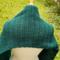 A close up of the scarf draped over the shoulders of the dress form. There is green grass in the background.