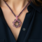 Closeup of Pink Petal Bloom necklace with beaded flower pendant on model wearing a navy blouse.