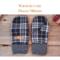 Pair of warm and cozy black and white plaid fleece regular sized women's mittens on rustic wood background — winter mittens for woman.