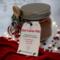 Christmas Hot Cocoa Jar on red cloth with lights and stars, cozy handmade cocoa gift for the holidays.