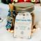 Winter Hot Cocoa Mix Jar with blue and silver ribbons resting on soft white fur holiday background.