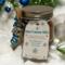 Hot Cocoa Jar with blue ribbon and snowflake tag displayed on snowy background with silver ornaments.