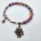 Handmade bracelet with purple beads, lavender stones, copper leaf beads, and a floral copper charm and copper pinecone charm