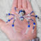 Handcrafted blue spider ornament made with glass beads, pearl like accents, and a decorative silver bead body.