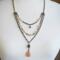 Handmade three-strand antiqued brass necklace with peach crystals, glazed agate beads, and a peach moonstone teardrop pendant.