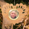 Wooden heart-shaped ornament with scalloped edges and an oak grain finish, featuring a removable round gold frame that holds a photo of a smiling blonde child.