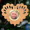 Wooden heart-shaped ornament with scalloped edges and an oak grain finish, featuring a removable round gold frame that holds a photo of a smiling blonde child.