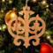 Intricate Victorian-style fretwork Christmas tree ornament handcrafted from natural hardwood with visible wood grain, showcasing symmetrical curls, loops, and ornate cut-out designs.