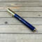 Gold magnetic cap rollerball pen with blue resin and pinecones 