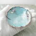 free form copper enamel trinket dish with opal and amethyst beads in palm of hand