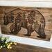 This is a large wood wall hanging featuring a bear and a forest scene. This piece is 36 inches wide and 20 inches tall. 