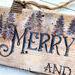 This is a close-up picture of wood-burned Christmas artwork. It shows Christmas trees and the word merry drawn in old-time lettering.