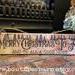 This is an old-time wood Christmas sign sitting on a fireplace hearth. The artwork is drawn by hand using pyrography. 