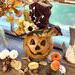 This is a fall table display featuring a pumpkin gourd named Briar. She is wearing a custom fall hat that is decorated with fall foliage. 