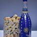 Hand painted blue bottle with various dot art/mandala designs around the entire bottle