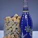 Hand painted blue bottle with various dot art/mandala designs around the entire bottle