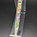 Picture of the bottom half of a pen in an acrylic holder. The pen is matte with rainbow colors marbled across it and matte pearl pen pieces.