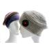 Mannequin in front wears a taupe Muffin-Top beanie that's adorned with a big, shiny black button.  In back, the mannequin wears a beanie in a self-striping yarn in earthy colors.