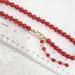 Red glass choker necklace, with beaded extender chain, shown next to a ruler.