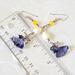 Yellow and purple crystal dangle earrings, next to a ruler.
