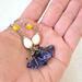 Handmade yellow and purple dangle earrings. Shown in hand, for size comparison.
