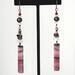 Long dangling pink gemstone earrings, with pearls and crystals. Shown on a display stand.