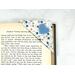A fun blue, peach color and white fabric corner bookmark with a blue heart applique.  The corner bookmark is being shown slid over a page of a book to show it in use.