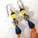 Close-up of yellow gemstones and blue crystals on a pair of earrings.