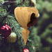 The wooden miniature Birdhouse Ornament is shaped like a heart. A small, dark-reddish-brown bird is perched on the front of the birdhouse. The heart-shaped structure has a pointed bottom that tapers down to a fine point. The wood is light beige.