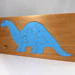 This is a handmade wooden dinosaur tray puzzle with a baby blue dinosaur. The tray is finished with amber shellac. It is lightly used but in like-new condition. This dinosaur is a freestanding and versatile toy for kids of all ages.