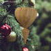 The wooden miniature Birdhouse Ornament is shaped like a heart. A small, dark-reddish-brown bird is perched on the front of the birdhouse. The heart-shaped structure has a pointed bottom that tapers down to a fine point. The wood is light beige.