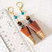 Wood dangle earrings, with blue crystals, shown next to a ruler.