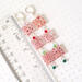 Red millefiori Christmas earrings, next to a ruler.