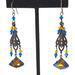 Long, boho dangle earrings, with blue and topaz crystals, shown on a display stand.