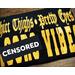 Folded Black t-shirt showcasing the shirt image.  Image is Olde English lettering on top of large block letters reading "Thicc Thighs - Pretty Eyes, A***o Vibes in Goldenrod Yellow vinyl .